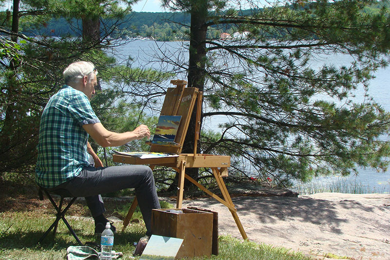 Artist painting by lake